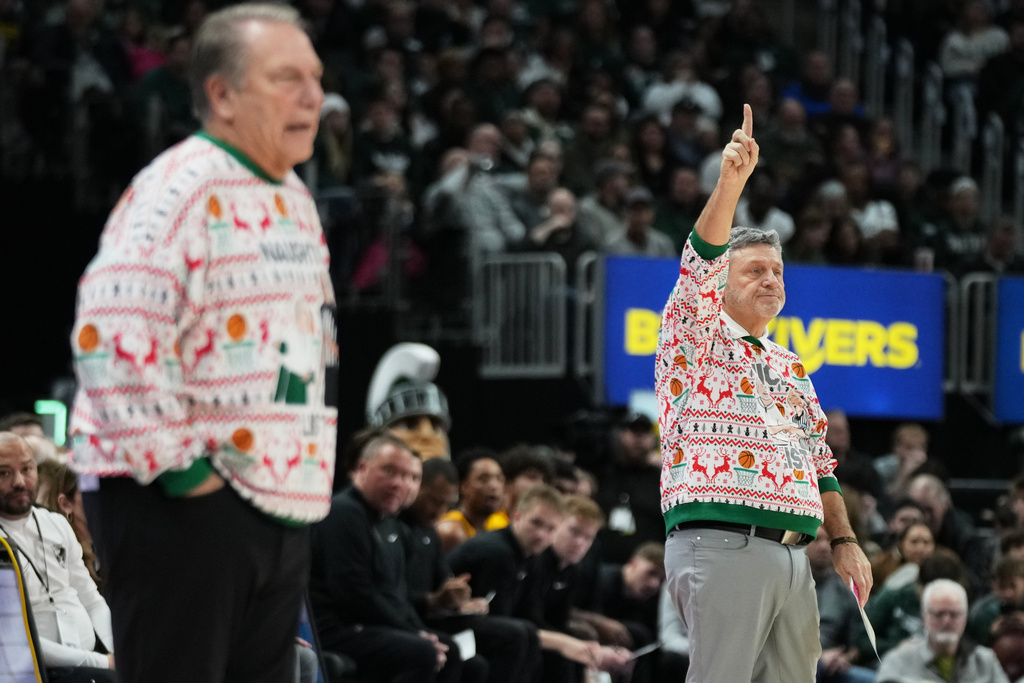 Oakland head coach Greg Kampe, right, gestures near Michigan State head coach Tom Izzo during the first half of an NCAA college basketball game, Saturday, Dec. 20, 2025, in Detroit. (AP Photo/Ryan Sun)