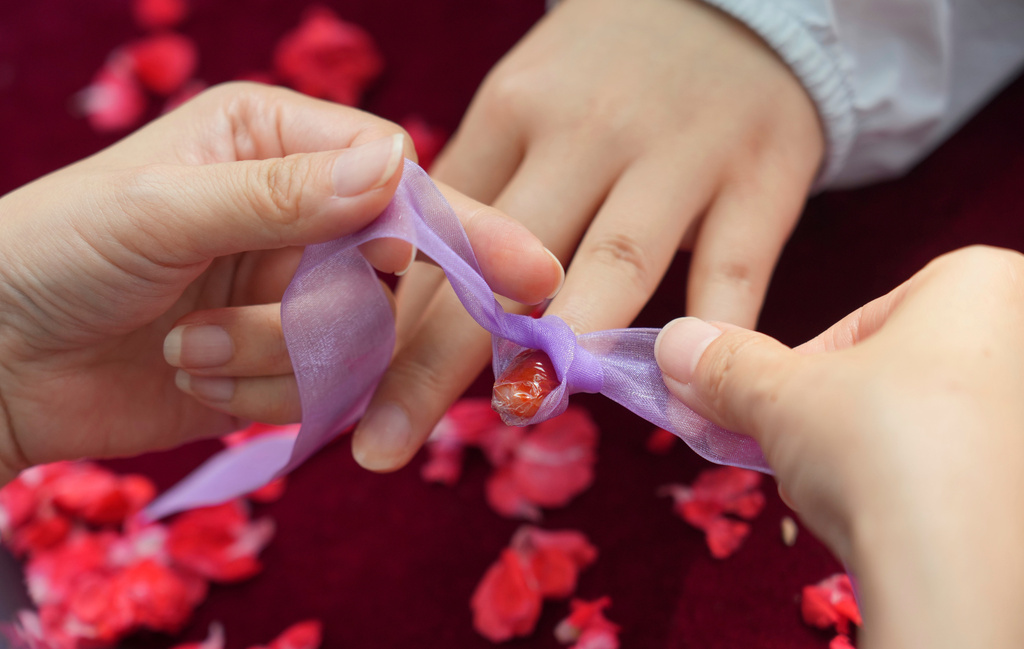 A woman gets her nail dyed with garden balsam, a natural pigment traditionally associated with beauty and blessings, during a festival to celebrate Qixi at the Beijing Folk Custom Museum in Beijing, Wednesday, Aug. 19, 2026. (AP Photo/Achmad Ibrahim)