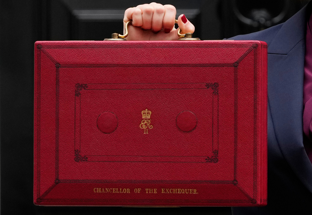 FILE - Britain's Chancellor of the Exchequer, Rachel Reeves, holds up the traditional red ministerial box containing her budget speech, as she poses for the media outside No 11 Downing Street, before departing to the House of Commons to deliver the budget in London, Wednesday, Oct. 30, 2024. (AP Photo/Kirsty Wigglesworth, File)