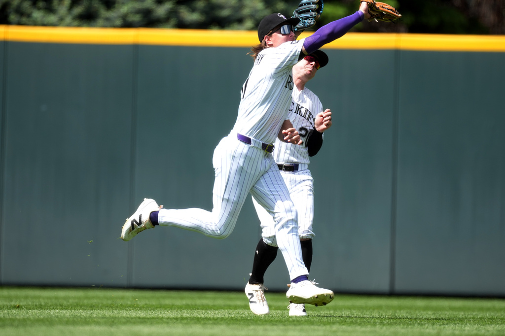Colorado Rockies center fielder Jake McCarthy, front, cuts off right fielder Troy Johnston to pull in a fly ball off the bat of New York Mets second baseman Marcus Semien in the sixth inning of a baseball game Thursday, May 7, 2026, in Denver. (AP Photo/David Zalubowski)