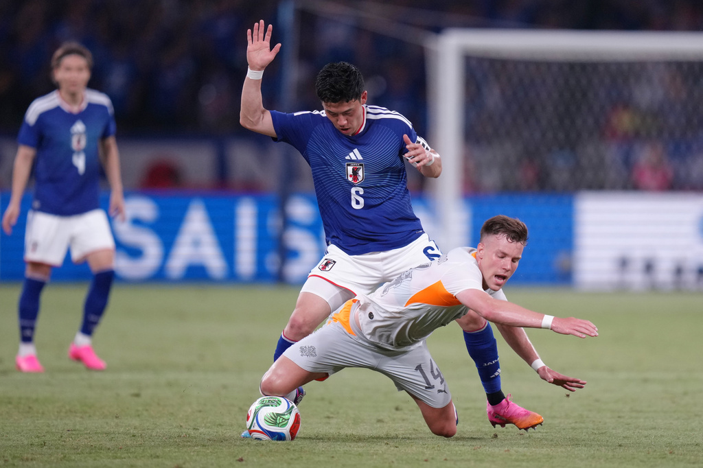 Andri Fannar Baldursson of Iceland falls as he battles for the ball with Wataru Endo of Japan during the friendly soccer international between Japan and Iceland in Tokyo, Sunday, May 31, 2026. (AP Photo/Eugene Hoshiko)