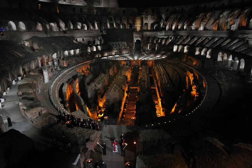 Pope Leo XIV carries a lightweight, 1.5-meter (5-foot) wooden cross during the Via Crucis, the torchlit Good Friday Stations of the Cross procession at the Colosseum in Rome, Friday, April 3, 2026, which symbolically retraces Jesus Christ's steps to his crucifixion on Calvary in Jerusalem. (AP Photo/Alessandra Tarantino)