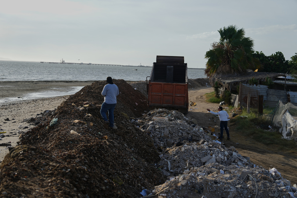 Workers build a barricade to help keep water out of their town as Hurricane Polo approaches in Puerto San Carlos, Baja California Sur state, Mexico, Sunday, Sept. 27, 2026. (AP Photo/Eduardo Verdugo)