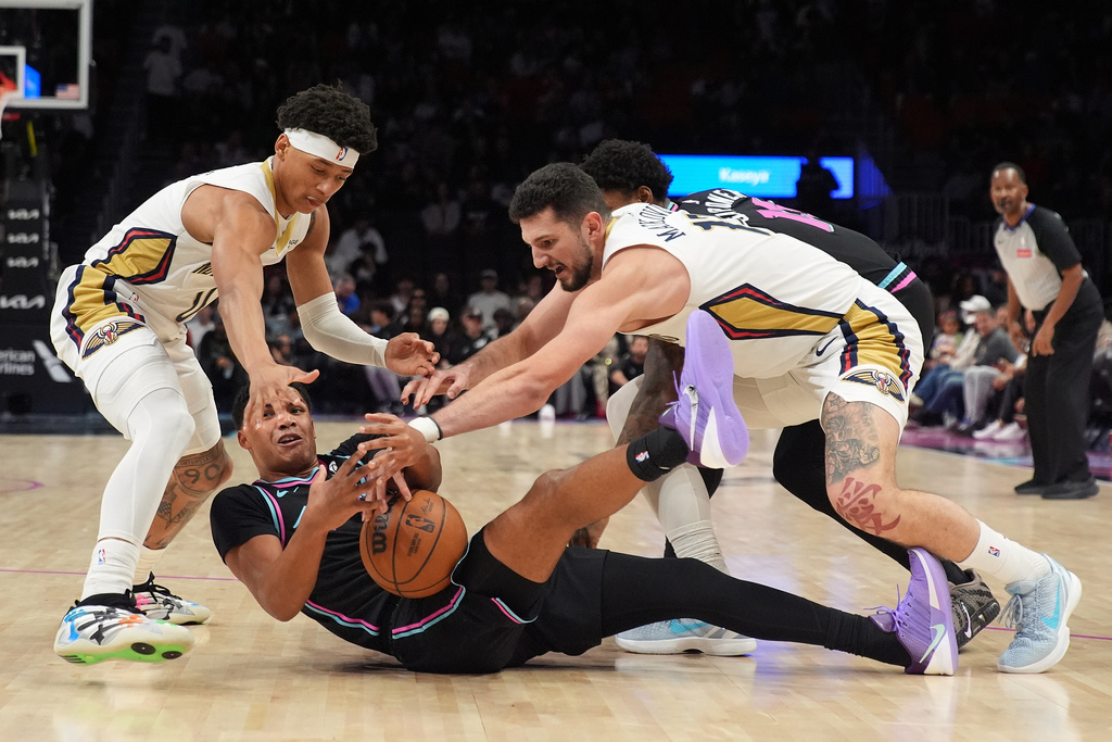 Miami Heat guard Dru Smith, bottom, and guard Jahmir Young (17), back, battle for a loose ball with New Orleans Pelicans guard Jeremiah Fears, left, and forward/center Karlo Matkovic (17) during the first half of an NBA basketball game, Sunday, Jan. 4, 2026, in Miami. (AP Photo/Rebecca Blackwell)