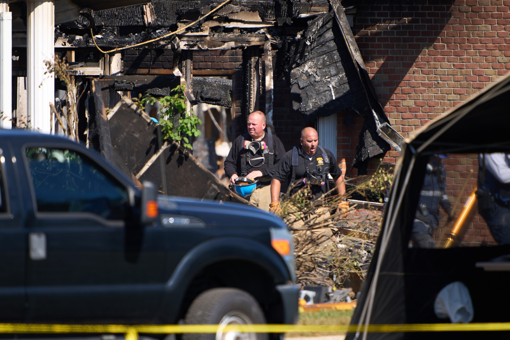 Investigators walk in The Church of Jesus Christ of Latter-day Saints in Grand Blanc Township, Mich. where Sunday morning a man rammed his vehicle into the building before opening fire and setting the building ablaze, Tuesday, Sept. 30, 2025. (AP Photo/Ryan Sun)