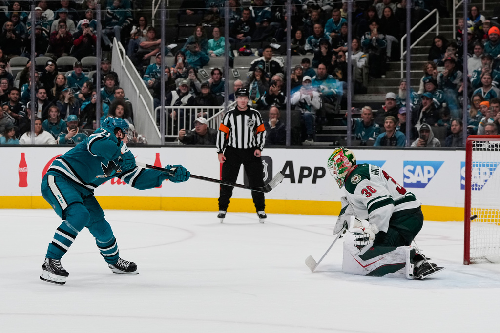 San Jose Sharks center Macklin Celebrini, left, scores against Minnesota Wild goaltender Jesper Wallstedt (30) in the shoot-out of an NHL hockey game, Wednesday, Dec. 31, 2025, in San Jose, Calif. (AP Photo/Godofredo A. Vásquez)