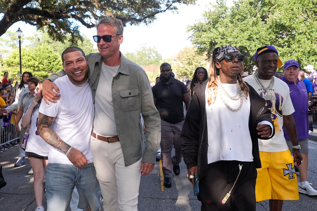LSU head coach Lane Kiffin walks down Victory Hill with former LSU and NFL player Tyrann Mathieu, left, and the LSU team, with rappers Lil Wayne, second at right, and Boosie, right, before an NCAA college football game against Louisiana Tech, Saturday, Sept. 12, 2026 in Baton Rouge, La. (AP Photo/Gerald Herbert)