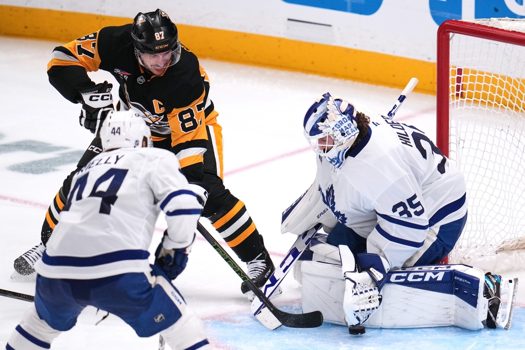 Pittsburgh Penguins' Sidney Crosby (87) backhands a shot past Toronto Maple Leafs goaltender Dennis Hildeby (35) for a goal with Morgan Rielly (44) defending during the third period of an NHL hockey game in Pittsburgh, Saturday, Nov. 29, 2025. (AP Photo/Gene J. Puskar)