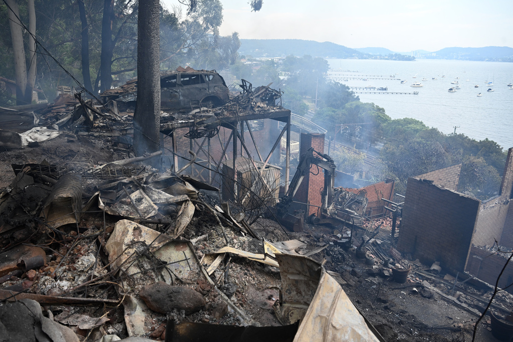 Ruins of buildings and a car smolder after a wildfire destroyed houses in Koolewong, Australia, Saturday, Dec. 6, 2025. (Dan Himbrechts/AAP Image via AP)