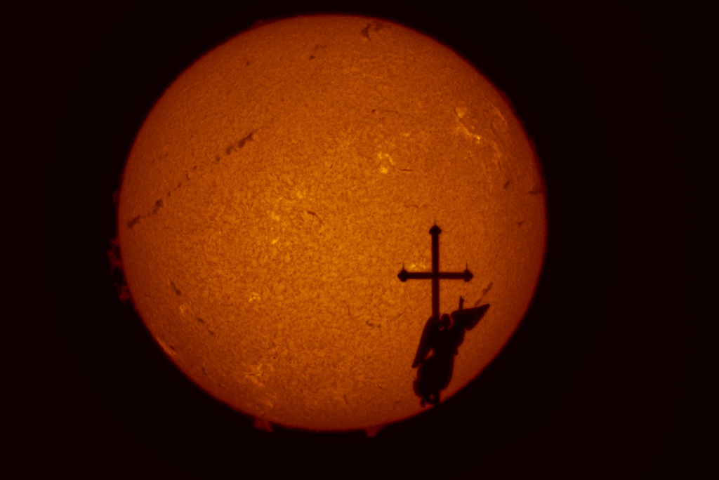 A weather vane in the form of an angel on top of the spire of the Saints Peter and Paul Cathedral is silhouetted against the sun showing solar activity zones, photographed by a solar telescope, in St. Petersburg, Russia, on Aug. 21, 2025. (AP Photo/Dmitri Lovetsky, File)