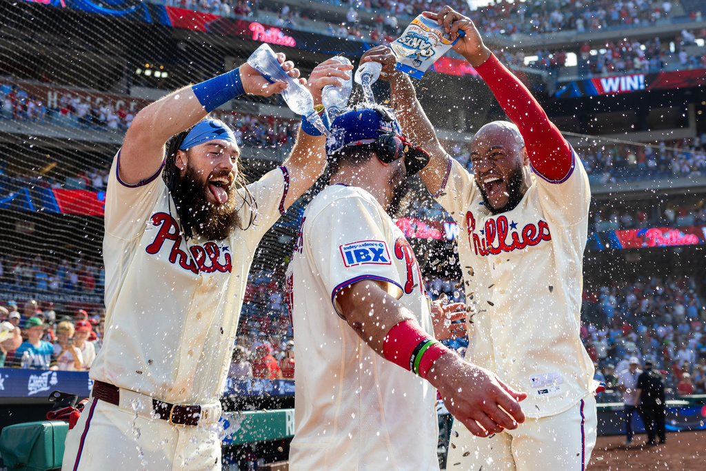 Philadelphia Phillies' Brandon Marsh, left and Bryan De La Cruz, right, douse Kyle Schwarber, center, after a baseball game against the St. Louis Cardinals, Sunday, Aug. 23, 2026, in Philadelphia. (AP Photo/Laurence Kesterson)