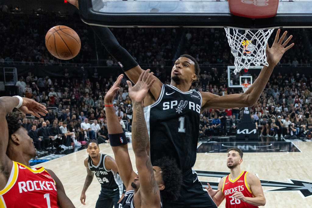 San Antonio Spurs forward/center Victor Wembanyama, center, reaches for a rebound with Houston Rockets guard Amen Thompson, left, during the first half of an NBA basketball game in Austin, Texas, Friday, Oct. 23, 2026. (AP Photo/Stephen Spillman)