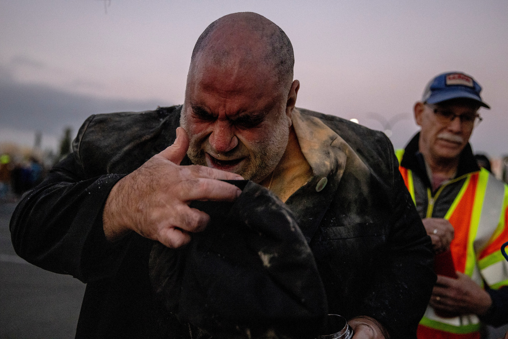 Jorge Bautista, a clergyman with the United Church of Christ, reacts after he was hit in the face by a pepper round from a U.S. Customs and Border Protection agent as protesters blocks the entrance to Coast Guard Island Alameda, where they are sent to as a staging area for the long-threatened immigration crackdown, in Oakland, Calif., Thursday, Oct. 23, 2025. (Stephen Lam/San Francisco Chronicle via AP)