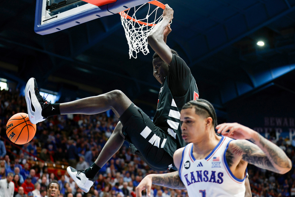 Cincinnati center Moustapha Thiam, top, dunks over Kansas guard Jayden Dawson (1) during the second half of an NCAA college basketball game, Saturday, Feb. 21, 2026, in Lawrence, Kan. (AP Photo/Colin E. Braley)
