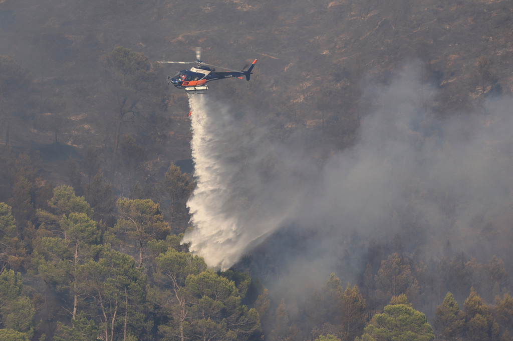 A firefighting helicopter releases water over a wildfire near Correns, southeastern France, Saturday, Aug. 1, 2026. (Clement Mahoudeau/Pool Photo via AP)
