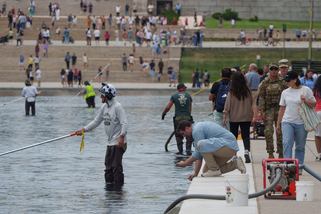 A visitor takes a photo as National Park Service employees work to clean the Lincoln Memorial Reflecting Pool Sunday, June 21, 2026, on the National Mall in Washington. (AP Photo/Jon Elswick