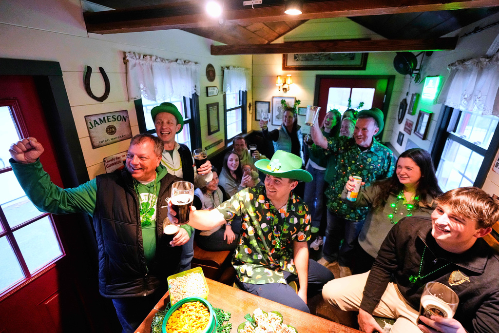 More than a dozen people pose for a photo while attending an early St. Patrick's Day party in a tiny pub rented by Mark Cote, third from right, Friday, March 13, 2026, in Andover, Mass. (AP Photo/Robert F. Bukaty)