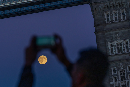 A person photographs the Harvest Supermoon as it rises behind Tower Bridge, Monday, Oct. 6, 2025, in London. (AP Photo/Julia Demaree Nikhinson) A person photographs the Harvest Supermoon as it rises behind Tower Bridge, Monday, Oct. 6, 2025, in London. (AP Photo/Julia Demaree Nikhinson)