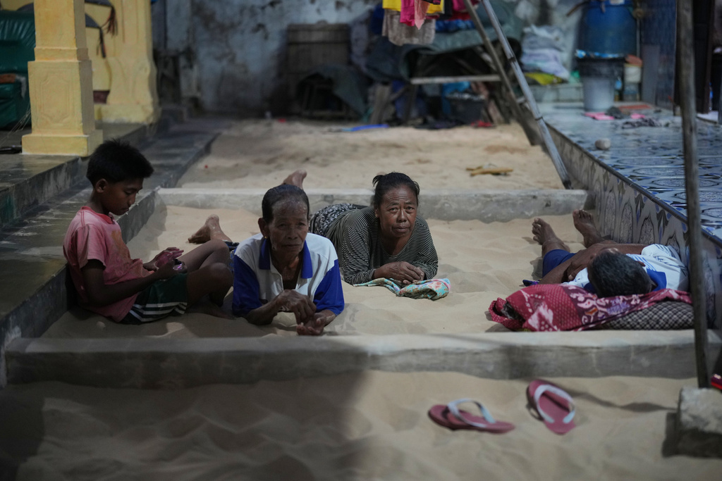 People lie in a sandpit, available in almost every house, in Legung Timur village in Sumenep on Madura Island, Indonesia, Tuesday, Sept. 9, 2025. (AP Photo/Dita Alangkara)