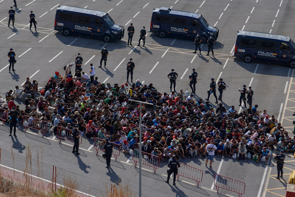 Migrants who crossed from Morocco into Spain are escorted by Spanish police to temporary shelters after being cleared from a beach in the Spanish exclave of Ceuta on Thursday, Aug. 20, 2026. (AP Photo/Antonio Sempere)
