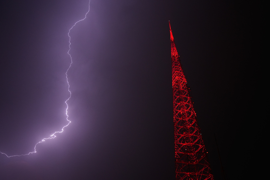 Lightning lights up the sky behind a television tower as a thunderstorm moves through the area Thursday, April 23, 2026, in Kansas City, Mo. (AP Photo/Charlie Riedel)