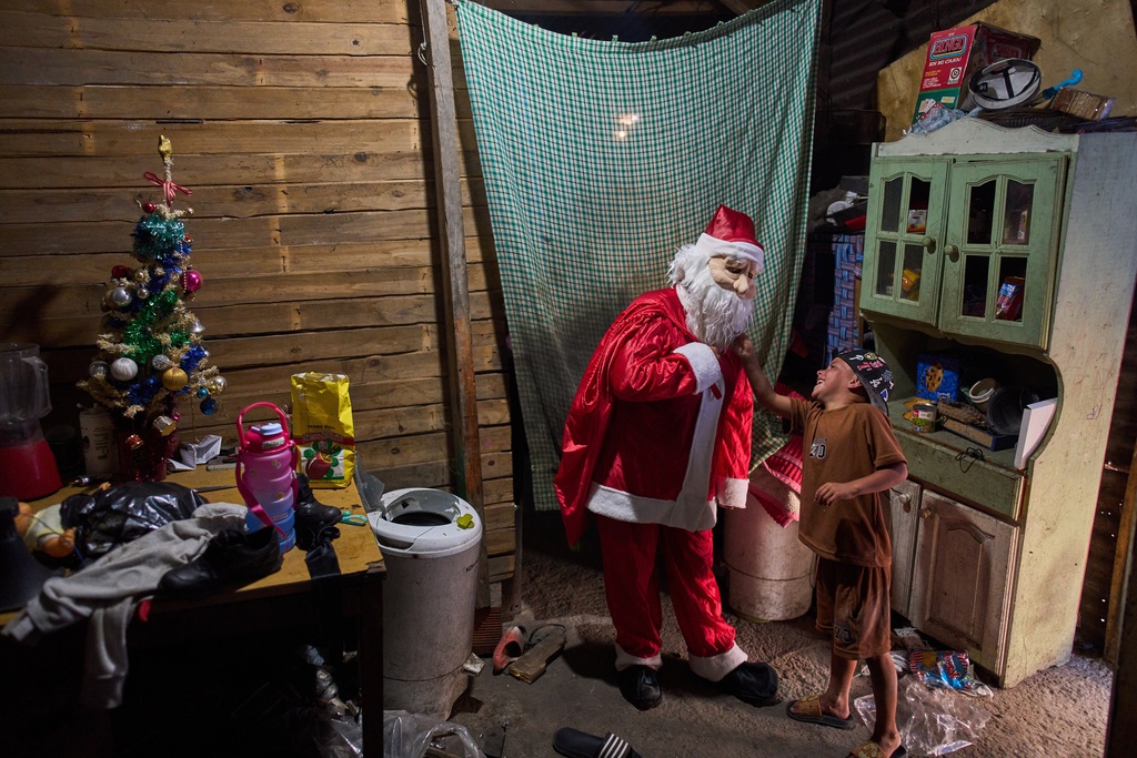 FILE - Cinthia Falcón, a neighbor dressed as Santa Claus, delivers gifts donated by NGOs during a celebration organized by a neighborhood soup kitchen in Lomas de Zamora, a suburb of Buenos Aires, Argentina, Dec. 27, 2025. (AP Photo/Rodrigo Abd, File)