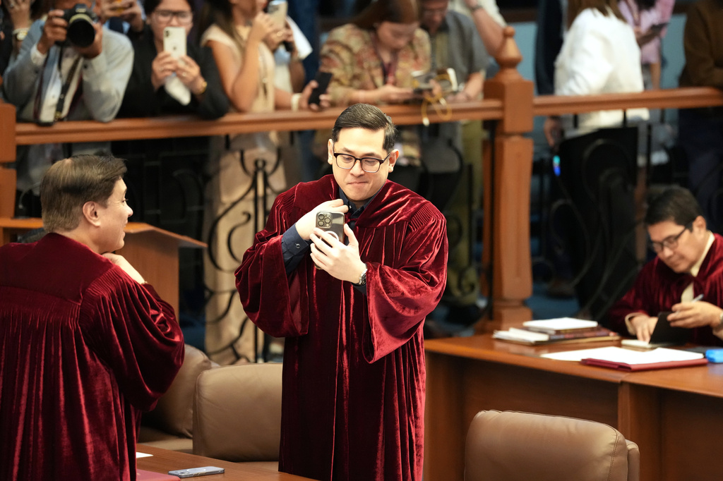 Philippine Senator Paolo Benigno "Bam" Aguirre Aquino IV, center, looks at his phone as they convene as an impeachment court for the trial of Vice President Sara Duterte at the Philippine senate, Monday, May 18, 2026, in Pasay, Philippines. (AP Photo/Aaron Favila)