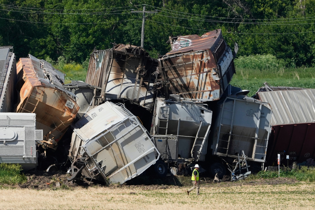 A worker walks past damage after a train derailed on Wednesday, June 3, 2026, near Victor, Iowa. (AP Photo/Charlie Neibergall)