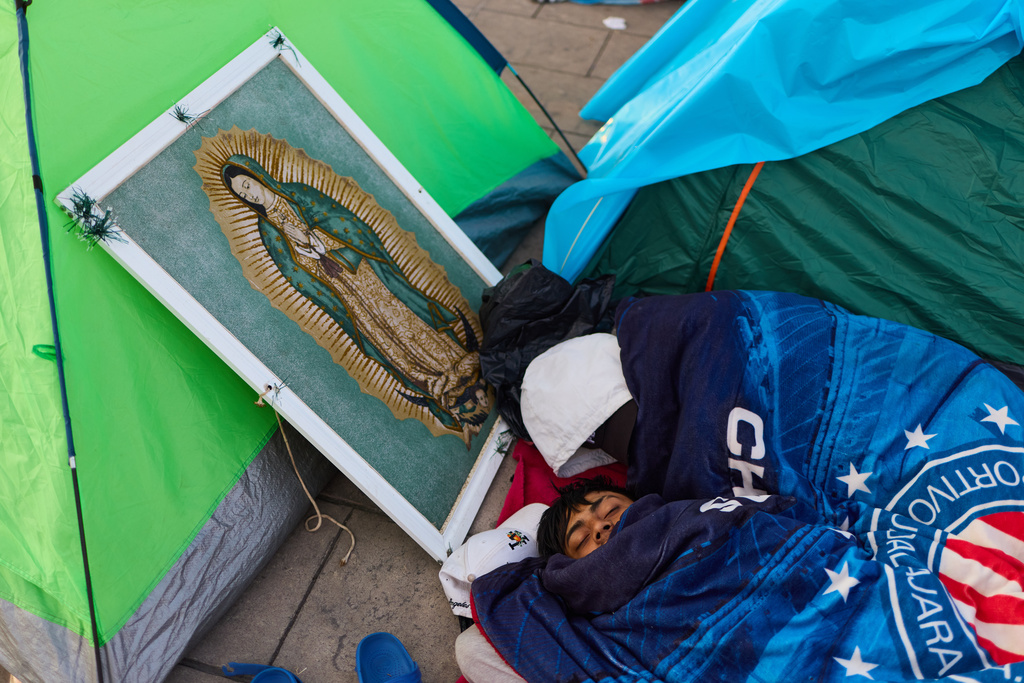 A pilgrim sleeps next to framed image of the Virgin of Guadalupe outside the Basilica of Guadalupe, in Mexico City, Thursday, Dec. 11, 2025, the day before her feast day. (AP Photo/Claudia Rosel)