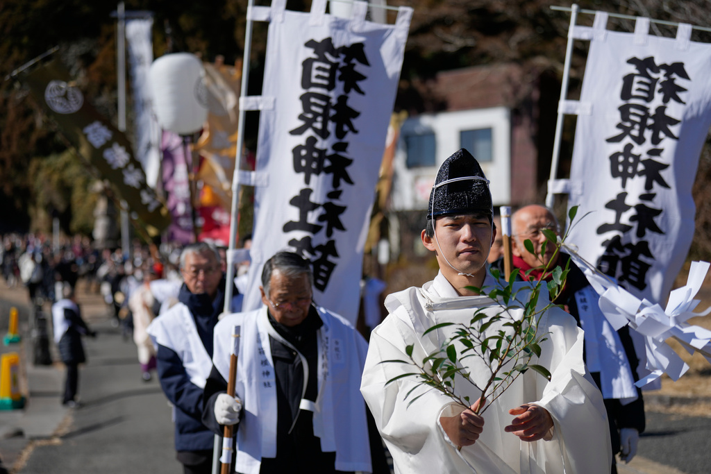 A priest leads participants towards Lake Ashi near Hakone Shrine during the annual Bean Throwing Festival in Hakone, Japan, Tuesday, Feb. 3, 2026. (AP Photo/Eugene Hoshiko)