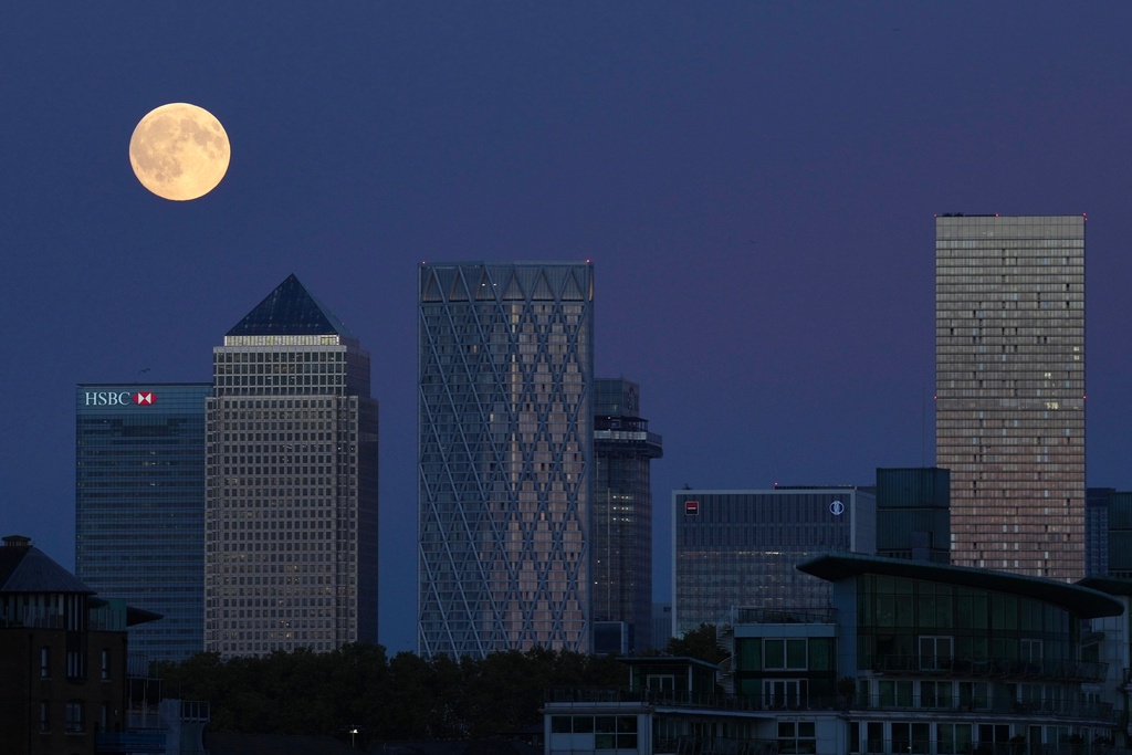 The Harvest Supermoon rises above Canary Wharf, in London, Monday, Oct. 6, 2025. (AP Photo/Kin Cheung)
