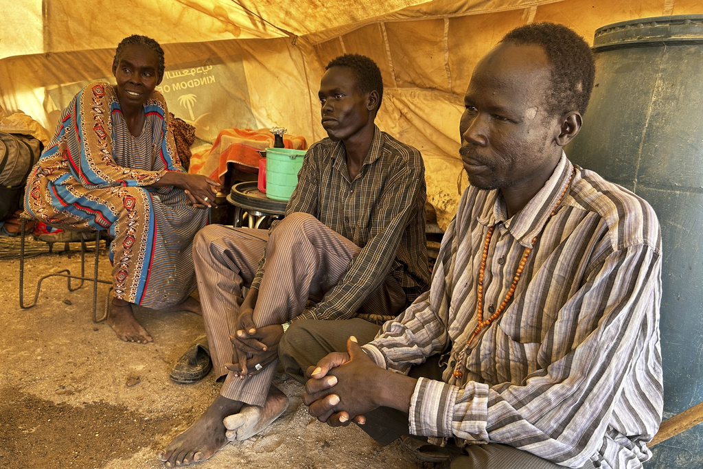 Daud Mahmoud Abdullah, 60, who says he spent six months in prison after being accused of cooperating with the Rapid Support Forces, sits with his wife and brother, whom he was reunited with at the Renk transit center, South Sudan, Saturday, Aug 9, 2025. (AP Photo/Adlai Coleman)