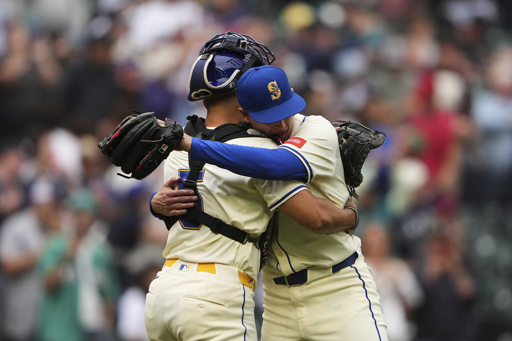 Seattle Mariners' Harry Ford (5) hugs relief pitcher Casey Legumina as they celebrate a win over the Los Angeles Angels in a baseball game Sunday, Sept. 14, 2025, in Seattle. (AP Photo/Lindsey Wasson)