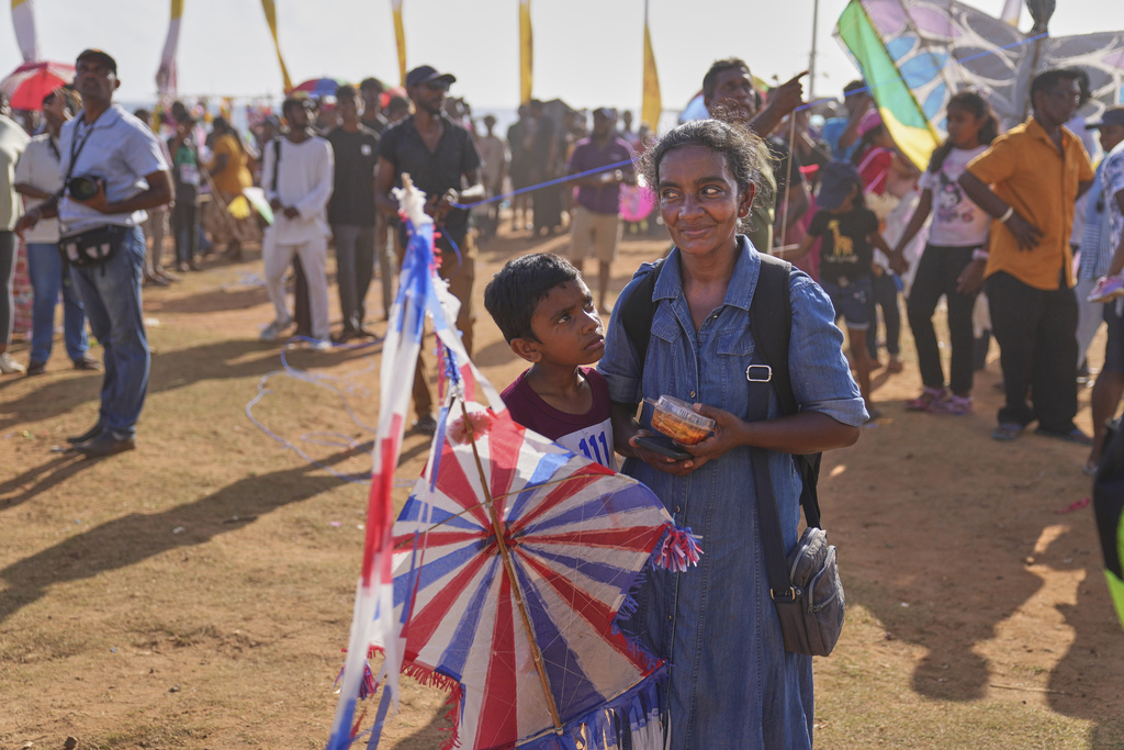 A Sri Lankan boy, accompanied by his mother, waits to fly his kite at the Colombo International Kite Festival in Colombo, Sri Lanka, Sunday, Aug. 24, 2025. (AP Photo/Eranga Jayawardena)