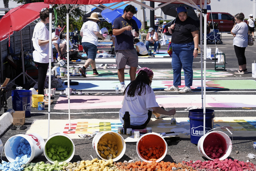 Artists paint parking spaces at a local restaurant to support the LBGTQ+ community and to protest state mandates on crosswalk art Monday, Sept. 15, 2025, in Orlando, Fla. (AP Photo/John Raoux)