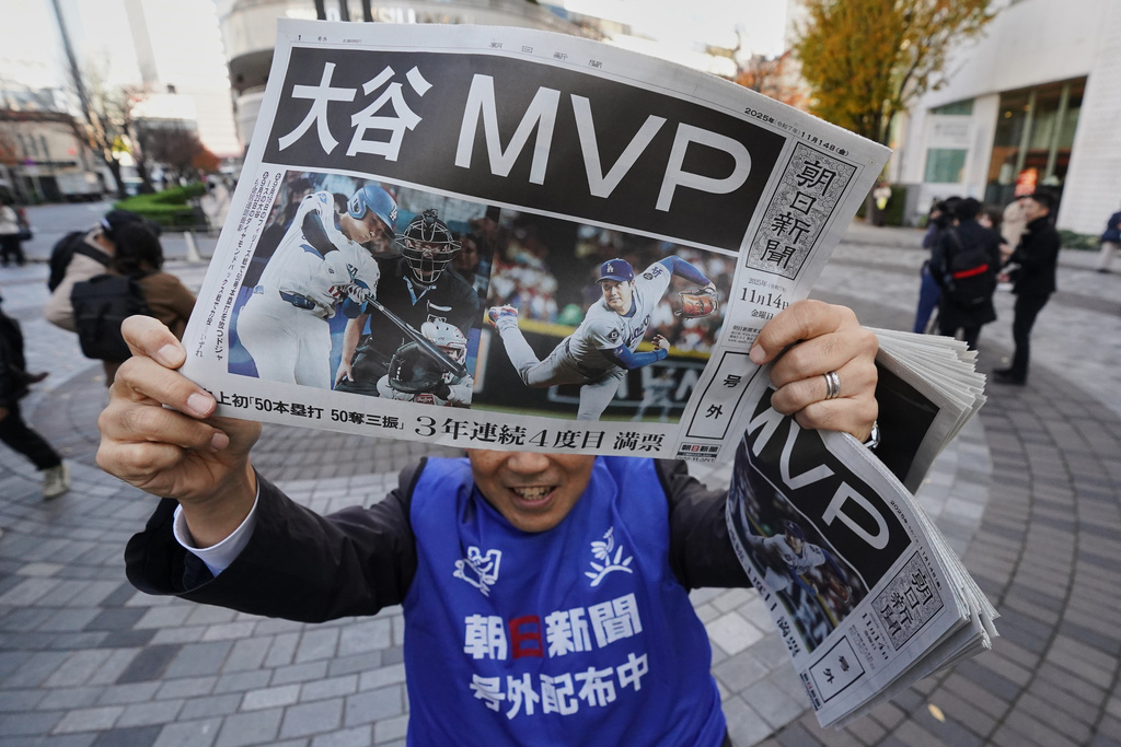 Staff of Japan's newspaper The Asahi Shimbun holds aloft a copy of the extra issue published after the Los Angeles Dodgers Shohei Ohtani won a Most Valuable Player award, in Tokyo, Friday, Nov. 14, 2025. (AP Photo/Koji Ueda)