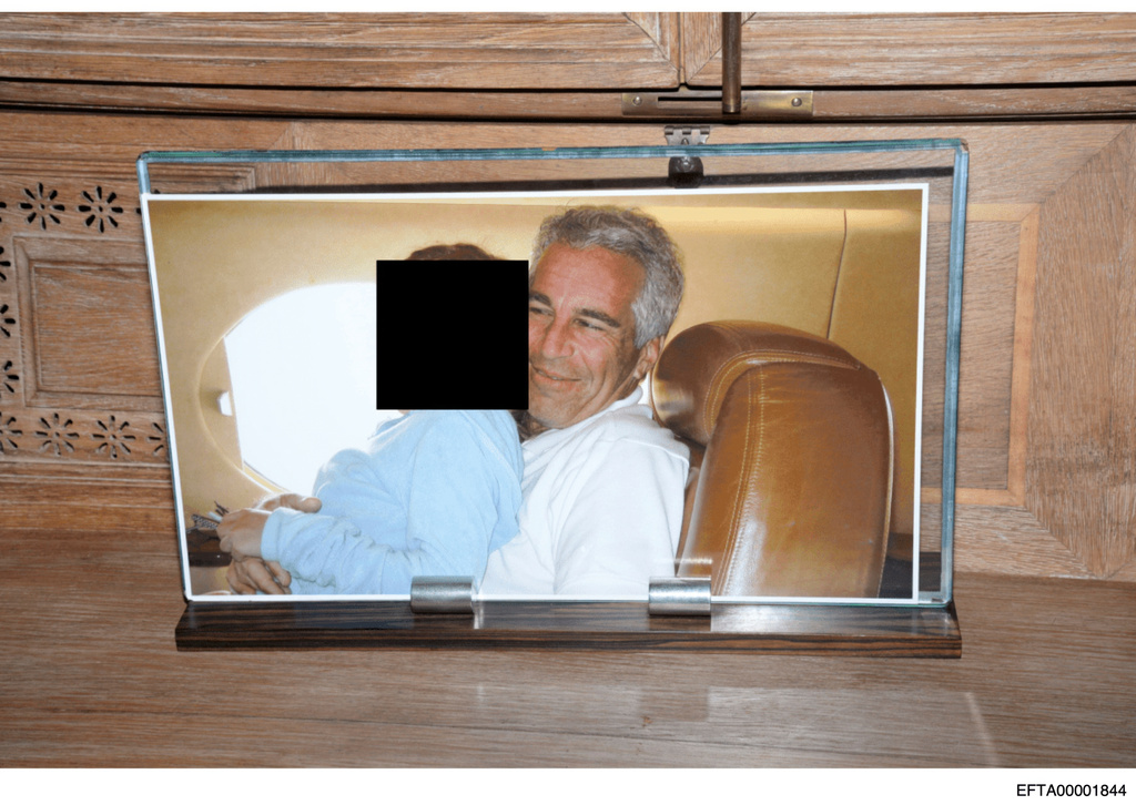This redacted photo released by the U.S. Department of Justice shows a framed photograph of Jeffrey Epstein with a person on his lap, documented on Aug. 12, 2019, during a search of his home on Little St. James island in the U.S. Virgin Islands. (U.S. Department of Justice via AP)