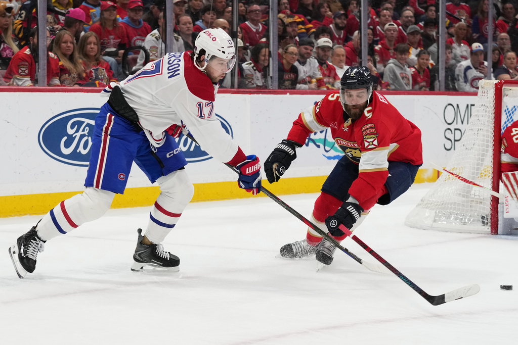 Montréal Canadiens right wing Josh Anderson (17) passes the puck as Florida Panthers defenseman Aaron Ekblad (5) defends during the first period of an NHL hockey game, Tuesday, Dec. 30, 2025, in Sunrise, Fla. (AP Photo/Lynne Sladky)