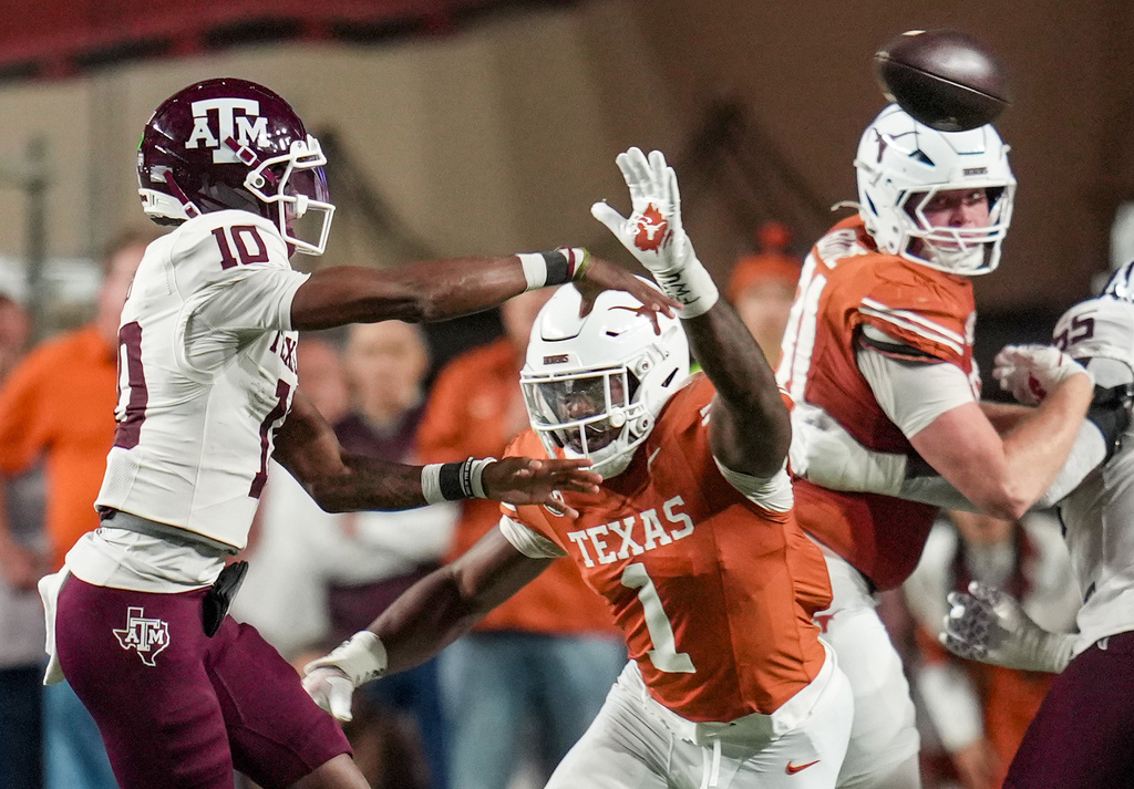 Texas defensive end Colin Simmons (1) tries to sack Texas A&M quarterback Marcel Reed (10) during the first quarter of an NCAA college football game in the Lone Star Showdown in Austin, Texas, Friday, Nov. 28, 2025. (Ricardo B. Brazziell/Austin American-Statesman via AP)