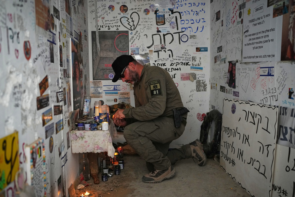 An Israeli soldier lights candles in a roadside bomb shelter where people were killed during the deadly Oct. 7, 2023, Hamas attack near the Israel-Gaza border, as Israel marks the second anniversary of the attack, Tuesday, Oct. 7, 2025. (AP Photo/Ohad Zwigenberg)