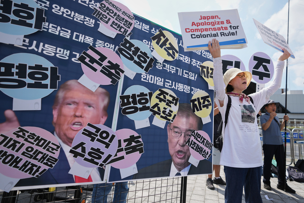 Members of civic group shout slogans next to pictures of U.S. President Donald Trump and Japanese Prime Minister Shigeru Ishiba during a rally ahead of South Korean President Lee Jae Myung's visit to Japan in Seoul, South Korea, Friday, Aug. 22, 2025. The part of letters read "Sovereignty and Peace." (AP Photo/Lee Jin-man)