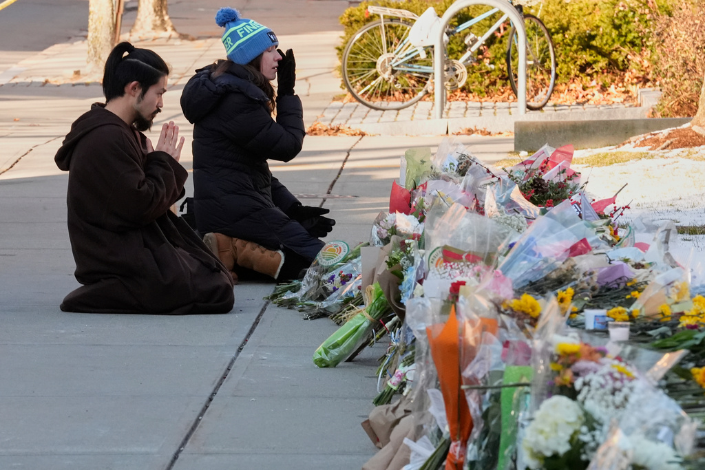 Visitors kneel at a makeshift memorial for the shooting victims outside the Engineering Research Center at Brown University, Tuesday, Dec. 16, 2025, in Providence, R.I.(AP Photo/Robert F. Bukaty)