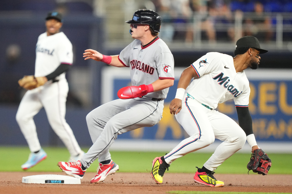 Cleveland Guardians' Travis Bazzana, center, advances to second base on a base hit as Miami Marlins shortstop Otto Lopez, right, tries to field the ball during the first inning of a baseball game, Saturday, July 11, 2026, in Miami. (AP Photo/Jim Rassol)