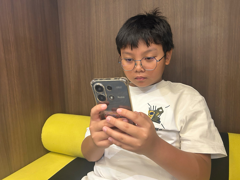 Hew Chee Weng, 11, uses a smartphone in Kuala Lumpur, Malaysia, Monday, June 1, 2026. (AP Photo/Syawalludin Zain)