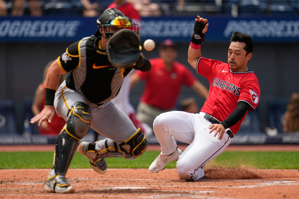 Cleveland Guardians' Steven Kwan, right, scores as Pittsburgh Pirates catcher Henry Davis, left, takes the throw in the third linning of the first baseball game of a split doubleheader in Cleveland, Saturday, June 18, 2026. (AP Photo/Sue Ogrocki)
