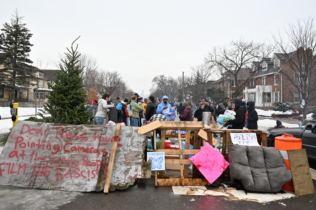People gather around a makeshift memorial honoring the victim of a fatal shooting involving federal law enforcement agents, near the site of the shooting, Thursday, Jan. 8, 2026, in Minneapolis. (AP Photo/Tom Baker)