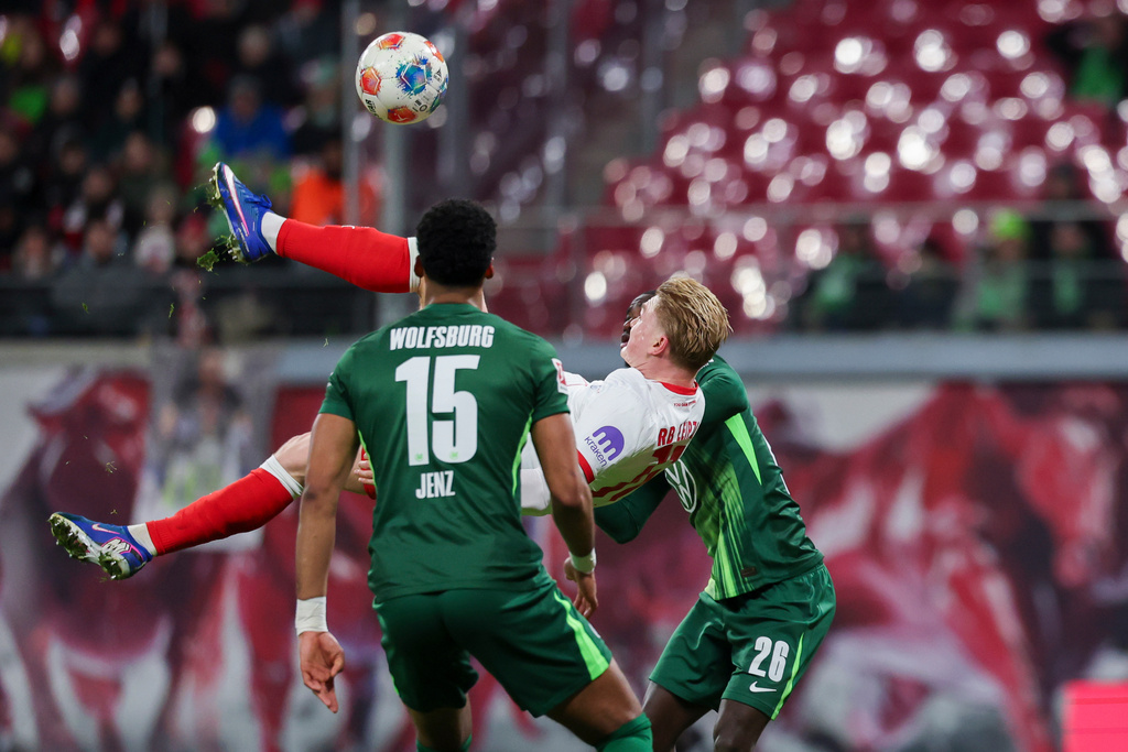 Leipzig's Conrad Harder, center, between Wolfsburg's Moritz Jenz, front, and Sael Kumbedi during the Bundesliga soccer match between RB Leipzig and VfL Wolfsburg in Leipzig, Germany, Sunday Feb. 15, 2026. (Jan Woitas/dpa via AP)