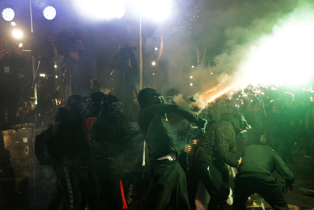 Hooded youth protesters throw flares and fireworks during an anti-government rally outside Prime Minister's office over corruption scandals and broader political issues, in Tirana, Albania, Tuesday, Feb. 10, 2026. (AP Photo/Hameraldi Agolli)