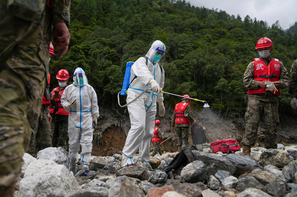 In this photo released by Xinhua News Agency, a worker carries out disinfection work as rescuers search for victims at a mudslide-hit area in Gyirong County, southwestern China's Tibet Autonomous Region, Sunday, Aug. 30, 2026. (Jigme Dorje/Xinhua via AP)