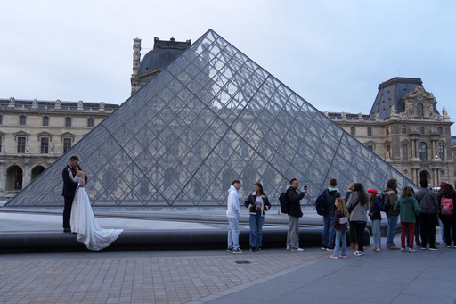 A wedding couple hugs as visitors queue to enter the Louvre museum three days after historic jewels were stolen in a daring daylight heist, Wednesday, Oct. 22, 2025 in Paris. (AP Photo/Thibault Camus) A wedding couple hugs as visitors queue to enter the Louvre museum three days after historic jewels were stolen in a daring daylight heist, Wednesday, Oct. 22, 2025 in Paris. (AP Photo/Thibault Camus)